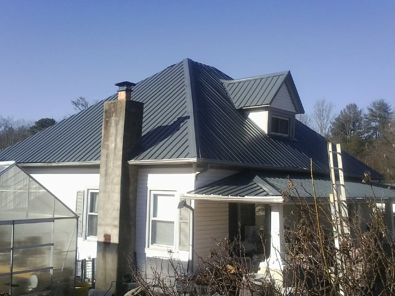 Dark blue standing seam metal roof on a white farmhouse with dormer — Slate & Tile Roof Repair by Roofing Brothers in Bucoda