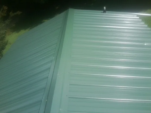 New green metal panels meeting at the ridge of a roof — Flat Roof Repair work by our crew in Bucoda