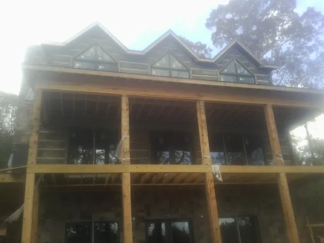 Dormers and porch framing on a large log home under construction — Roof Coating work by our crew in Bucoda