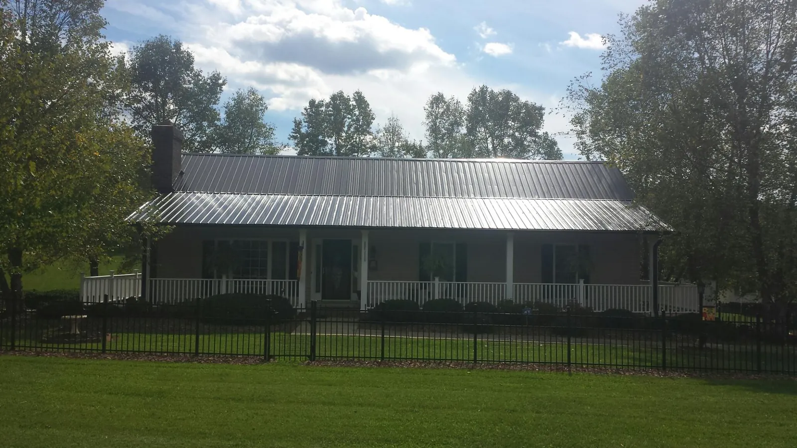 Gray metal roof on a brick ranch with a full width front porch — Gutter Guard Installation work by our crew in Bucoda