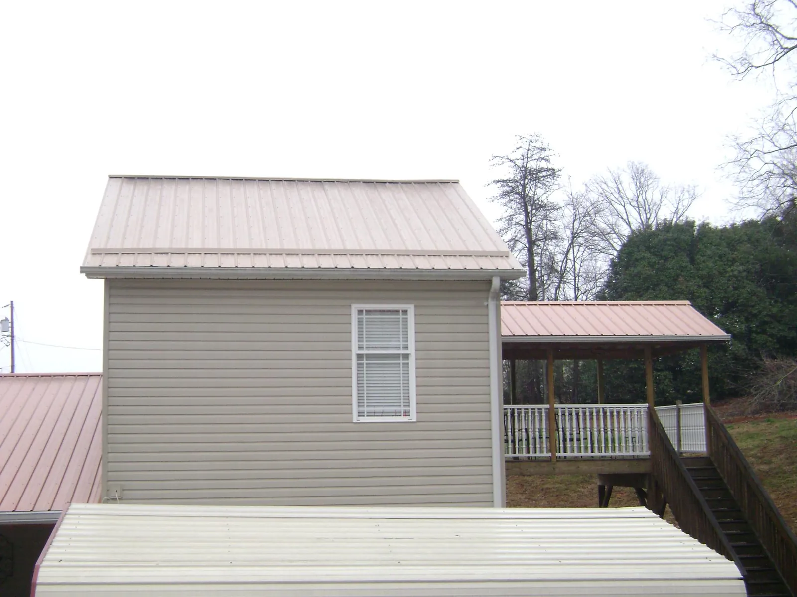 Tan metal roofs on a two story addition and attached porch, from a Roof Replacement job in Bucoda