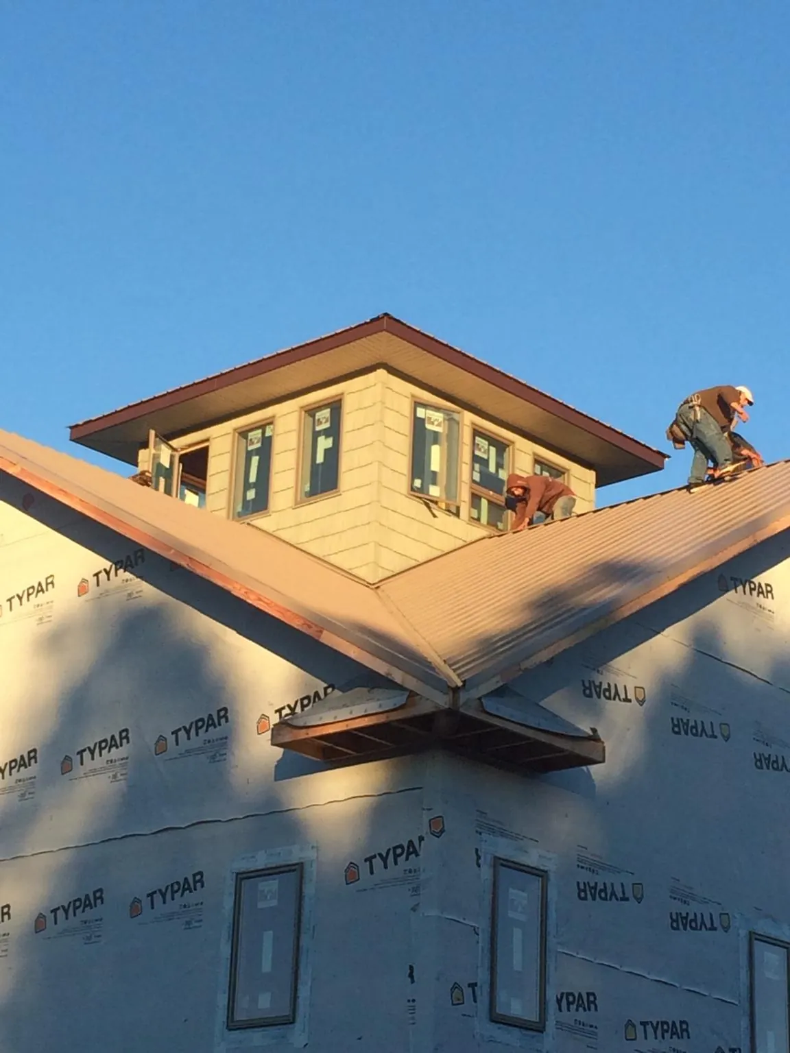 Roofers working around a rooftop cupola on a new metal roof at sunset — Roof Waterproofing in Bucoda by Roofing Brothers